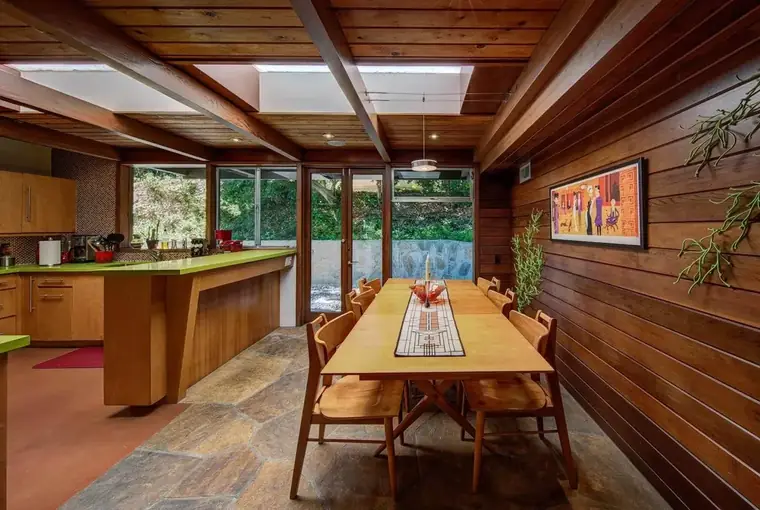 Wood-paneled kitchen and dining room with a long timber table