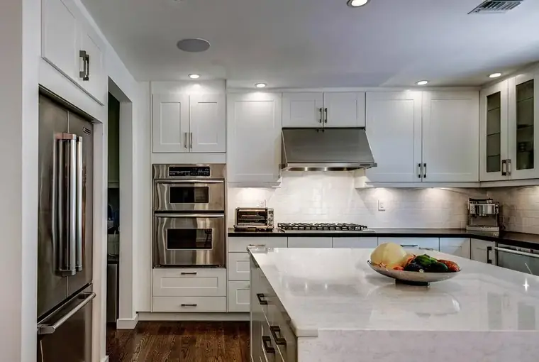White kitchen with marble island and stainless appliances