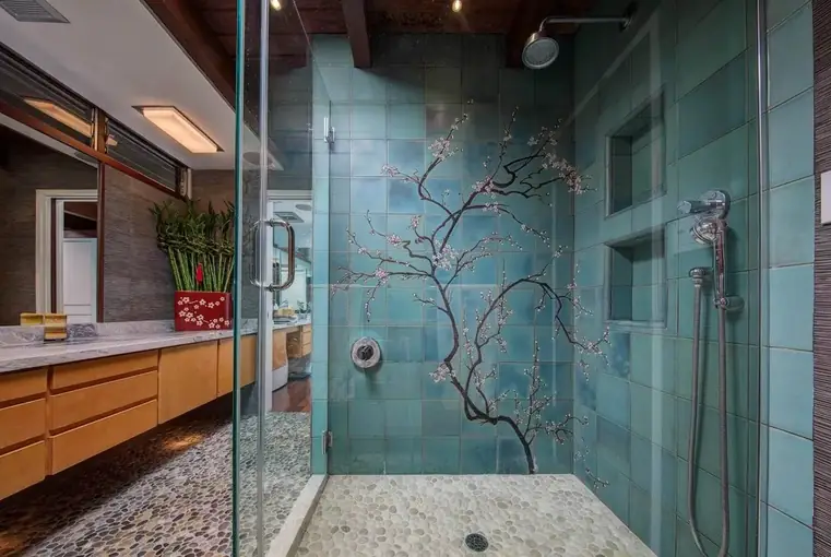 Glass shower with a blue tile wall and pebble floor